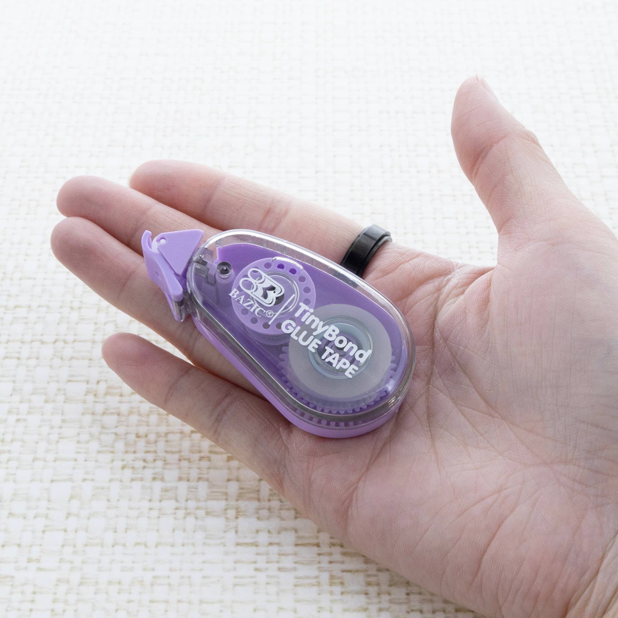 Purple glue tape dispenser held in a hand on a white background
